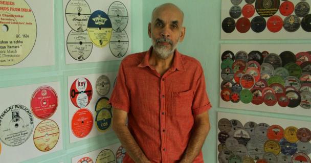 Dr Suresh Chandvankar standing next to his collection of records